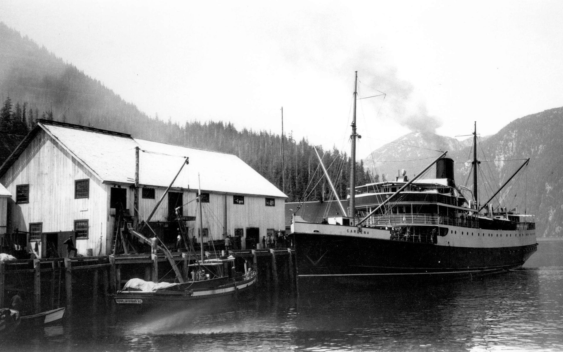 Cannery building with large steamship docked at the wharf.