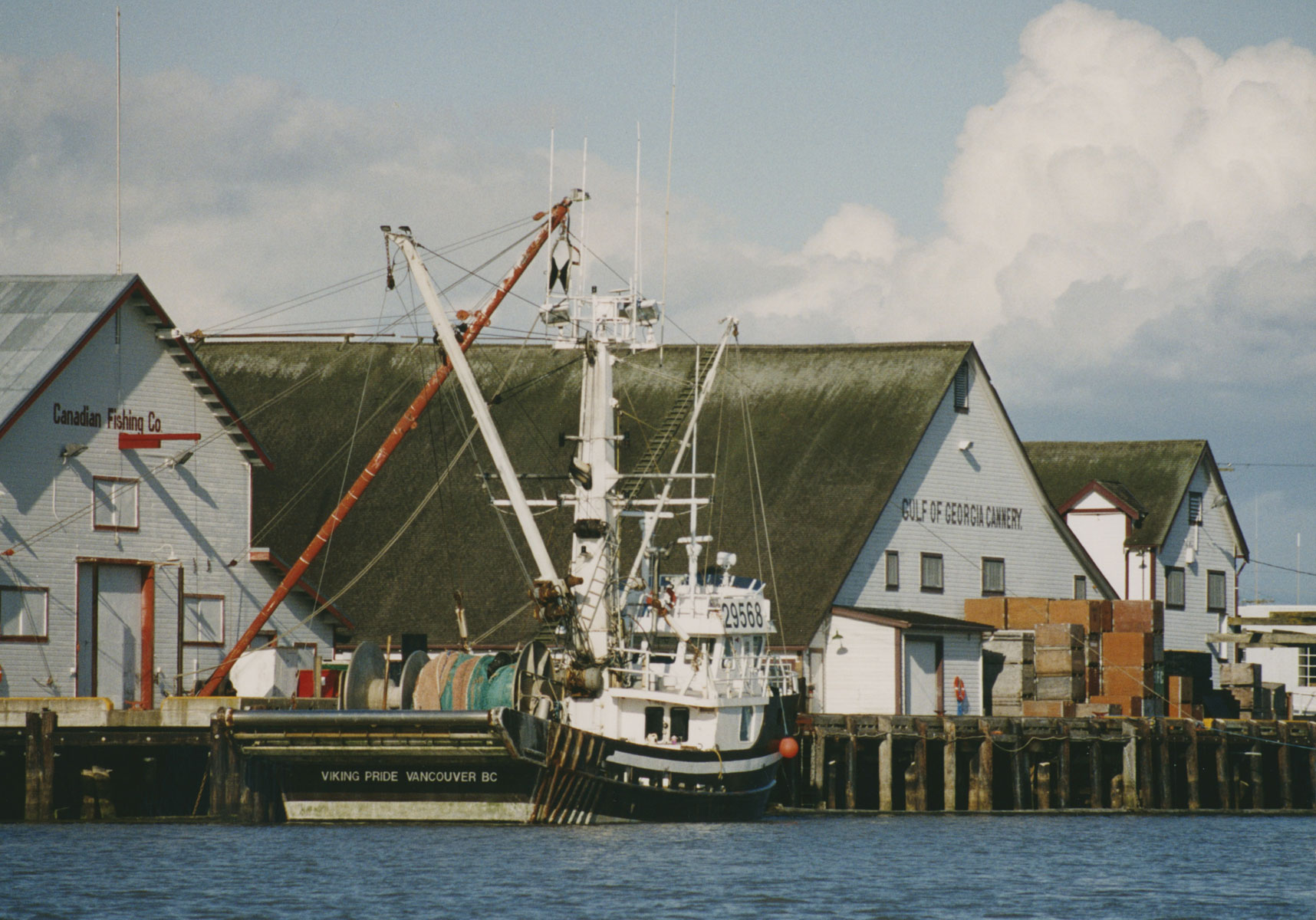 The Gulf of Georgia Cannery with a seine boat at the dock. The boat's name, Viking Pride, is on the stern. The buildings at the cannery have Canadian Fishing Co. and Gulf of Georgia Cannery painted on them.