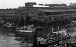 L'usine de la compagnie Canadian Fishing avec des bateaux de pêche entourant le bâtiment.