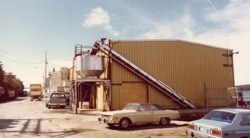 Vue extérieure d'un bâtiment avec plusieurs autos stationnées autour.