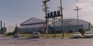 Les bâtiments de la conserverie Paramount vus du terrain de stationnement de la compagnie. Le nom « Paramount Cannery , Nelson Bros. Fisheries Ltd. » est peint sur le côté du bâtiment.