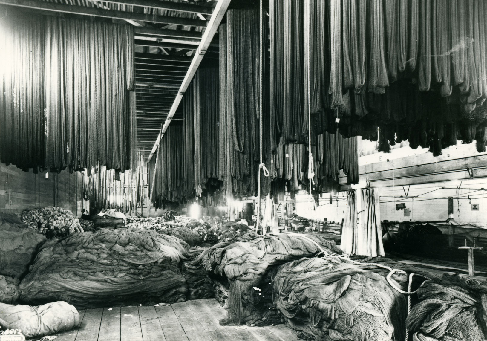 A large open room is filled with nets both hanging and piled on the floor.