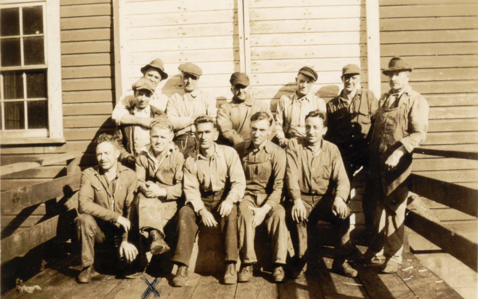Douze hommes employés de conserverie assis sur le quai à Butedale.