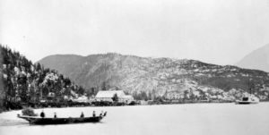 Five figures in a canoe in front of the Croasdaile Cannery.