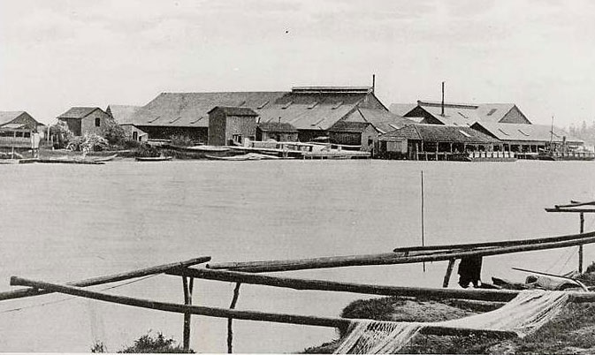 Cannery buildings across the river. Nets on net racks visible in the foreground.