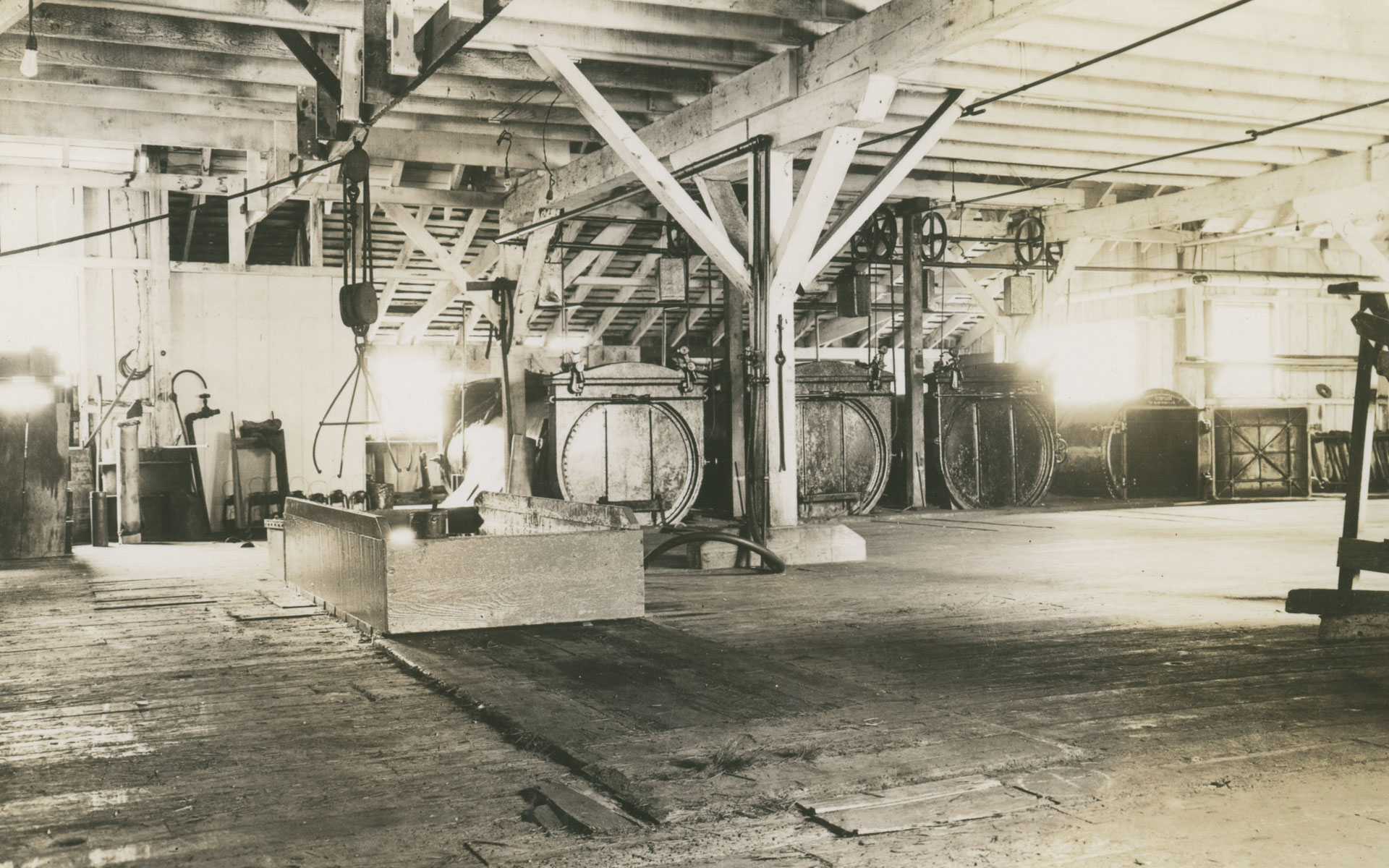 Interior of the Gulf of Georgia Cannery showing a large open space with three steam cookers and other machinery in the background.