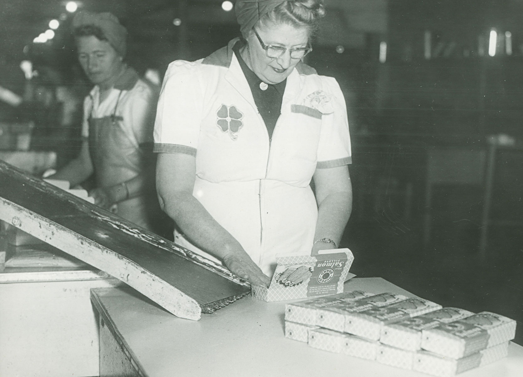 Women in Cloverleaf uniforms packing Rupert Brand frozen salmon fillets in boxes.