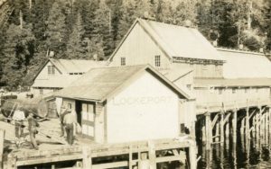 La conserverie Lockeport avec des travailleurs sur le quai avant. Le nom Lockeport est peint sur le côté du bâtiment.