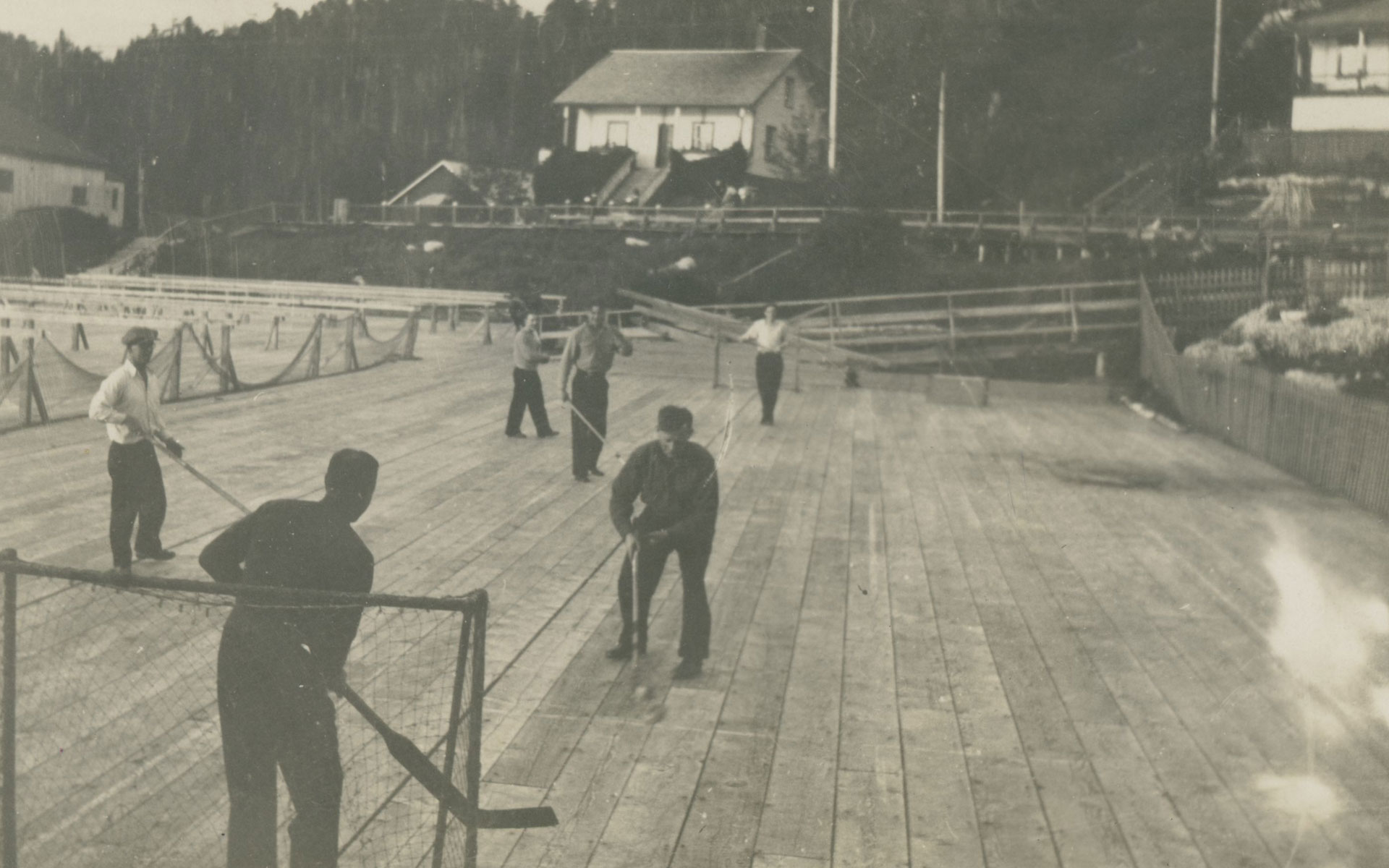 Six men playing hockey amongst the net racks on the dock at Namu.