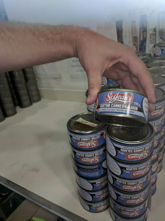 Stacks of canned salmon from the St. Jean's Cannery with labels that say "St. Jean's Custom Canned Salmon hand filleted- packed by hand."