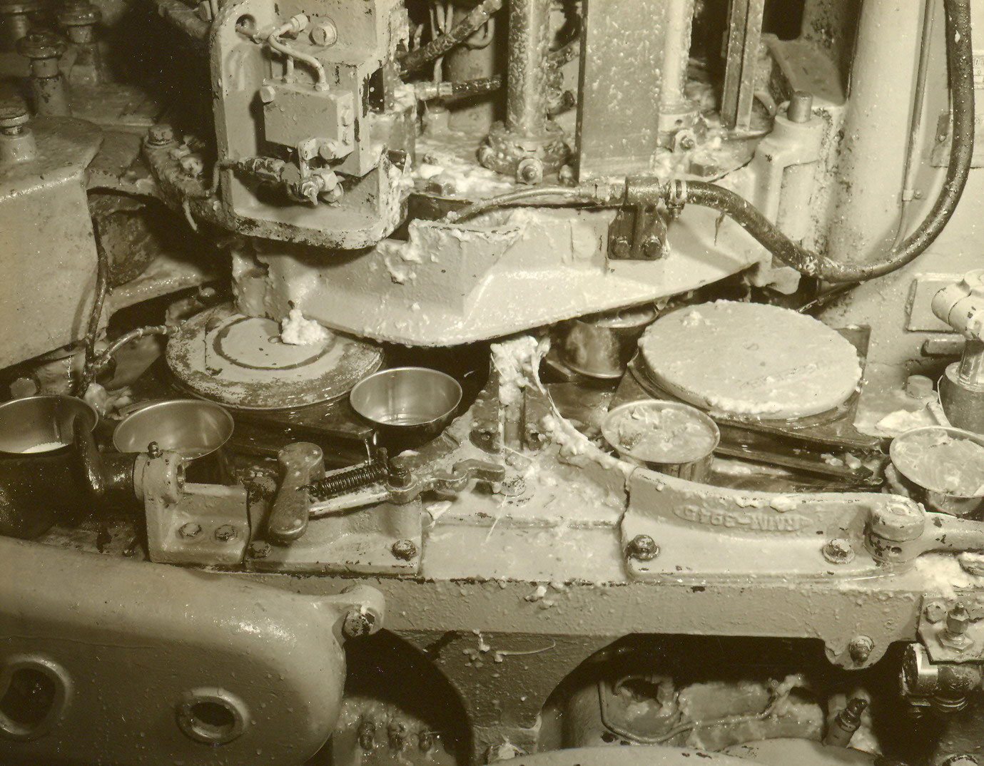 Close up photograph showing the part of the machine where the empty cans enter and filled cans exit.