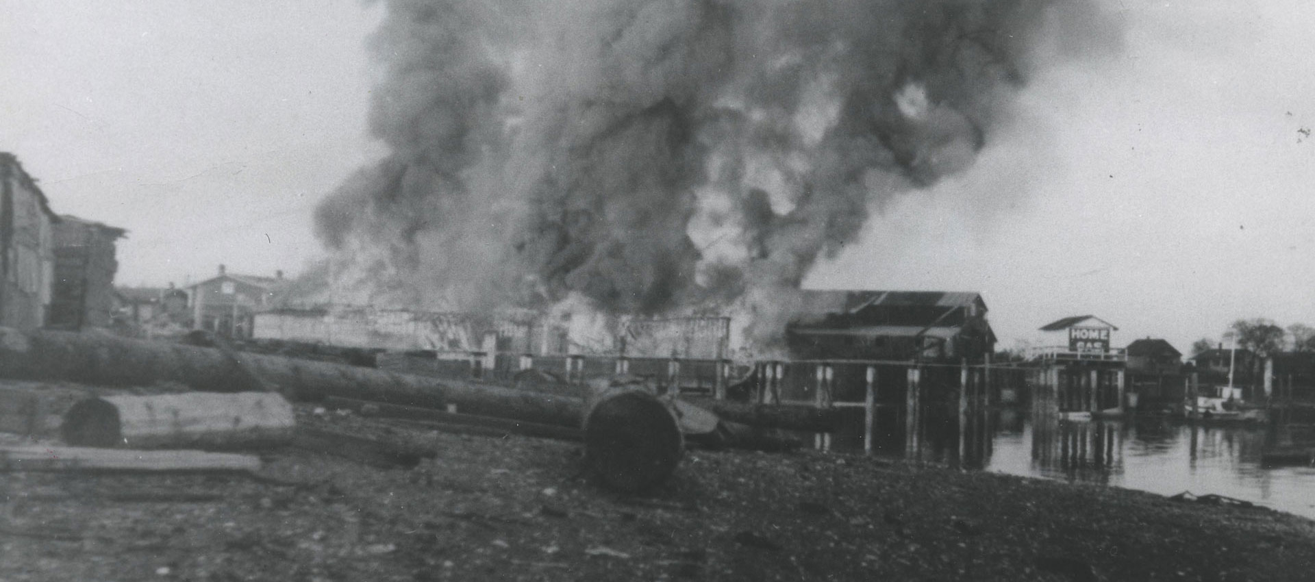 Large plume of dark smoke is rising from a cannery building.