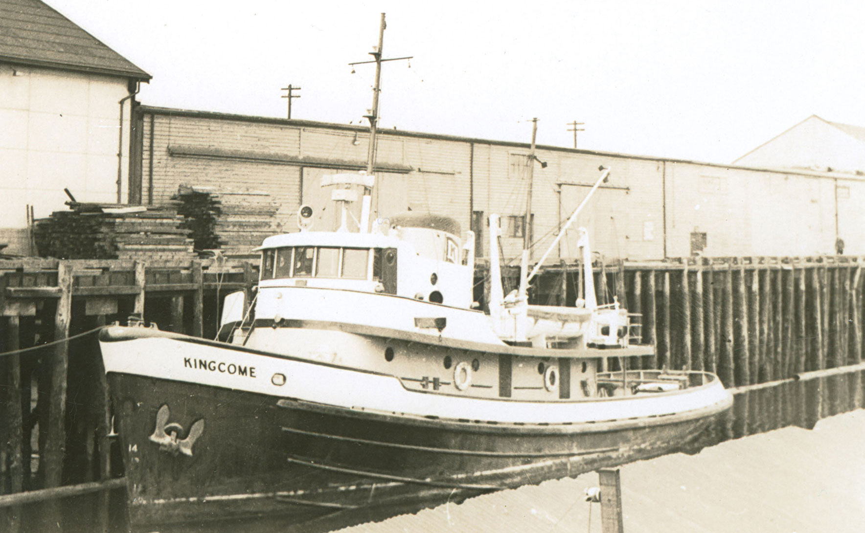 Vessel named "Kingcome" moored at a dock in front of cannery buildings
