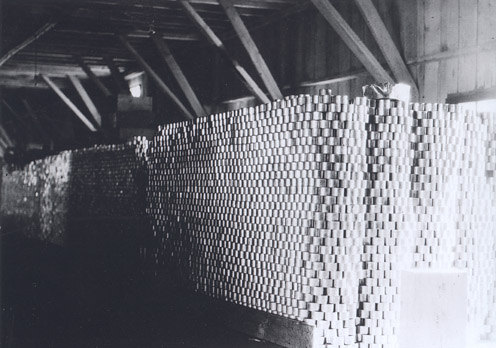 Cans are stacked to the rafters inside a wooden building.